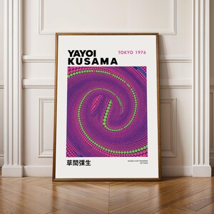 Può includere: Una stampa artistica incorniciata con un design astratto vibrante con un motivo a spirale nei toni del viola, rosa e verde. La stampa include il testo "YAYOI KUSAMA TOKYO 1976" e caratteri giapponesi. L'opera d'arte è esposta su una parete bianca.