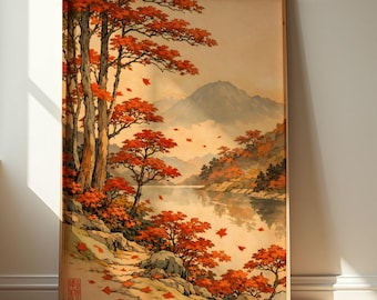 May include: A framed landscape print depicting a tranquil lake scene with vivid red autumn trees and falling leaves. The artwork shows a mountain range in the background, with a soft, warm colour palette. The print is in a wooden frame.