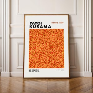 Può includere: Una stampa artistica incorniciata con il nome "YAYOI KUSAMA" in testo nero sopra un motivo di cerchi arancioni e rossi su sfondo giallo. La stampa include il testo "TOKYO 1990" e caratteri giapponesi. La cornice è di colore marrone caldo.