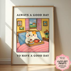 Può includere: Una stampa incorniciata con un gatto dei cartoni animati a letto, con un vassoio con un cupcake e una tazza di caffè. Il testo recita "ALWAYS A GOOD DAY TO HAVE A GOOD DAY". La stampa è in una cornice di legno.