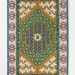 May include: A rectangular rug with a green central field, featuring white floral and blue circular patterns. The rug has a pink border with floral motifs and a teal outer edge. The design is symmetrical and detailed, suitable for home decor.