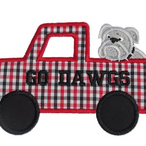 May include: Red and black checkered truck with a bulldog peeking out of the bed. The truck has black wheels and the words "Go Dawgs" are embroidered on the side.