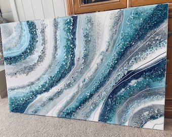 Puede incluir: Pintura abstracta con remolinos y purpurina azules, blancos y plateados. La pintura tiene un aspecto texturizado y en capas.