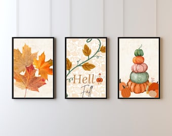 May include: Three framed art prints with fall themes. One features autumn leaves in shades of orange and brown. Another has the text "Hello Fall" with a pumpkin illustration. The third print shows a stack of pumpkins.