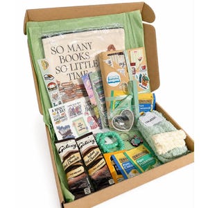 Könnte beinhalten: Eine Geschenkschachtel aus Karton mit einer Stofftasche mit dem Text SO MANY BOOKS SO LITTLE TIME, zwei Päckchen Galaxy Instant-Trinkschokolade, Twinings-Teebeuteln, hellgrünen flauschigen Socken, einem grünen Haargummi und verschiedenen Aufklebern.
