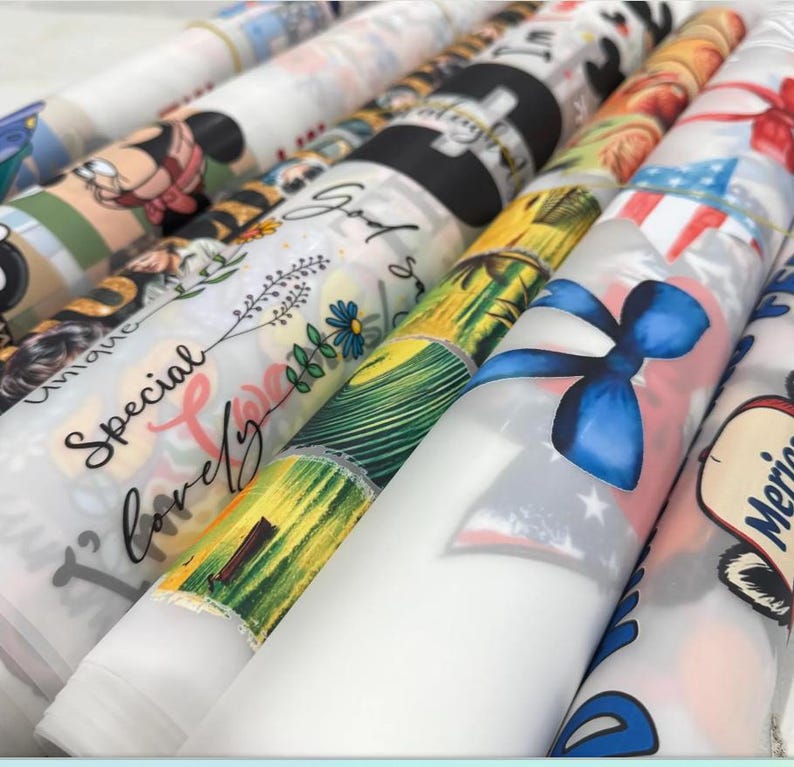 a collection of colorful, patterned fabric rolls or sheets, each with unique designs and text printed on them.