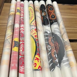 a collection of colorful, patterned, and textured rolls of paper or fabric, arranged on a wooden surface.