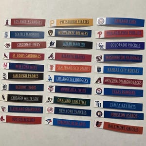 May include: A collection of baseball team logo stickers, including the Los Angeles Angels, Pittsburgh Pirates, and Chicago Cubs. Each sticker features the team name and logo on a colored background.