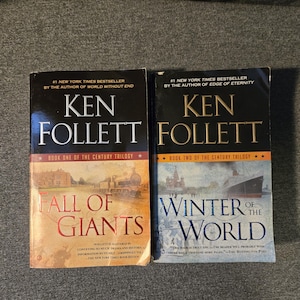 Peut inclure: Deux livres de Ken Follett, "Fall of Giants" et "Winter of the World", de la trilogie du siècle. Le premier livre présente une illustration de train, le second un navire. Les deux sont des best-sellers du New York Times.