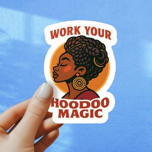 May include: A sticker featuring a profile of a Black woman with braided hair, gold earrings, and a red top, set against an orange circle. The text "WORK YOUR HOODOO MAGIC" is displayed in a red, stylized font.