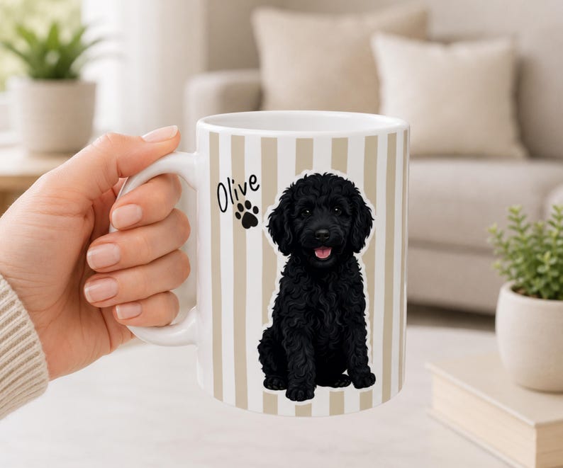 May include: White ceramic mug with vertical beige stripes, featuring a black dog illustration and the name "Olive" with a paw print. The mug has a white handle.