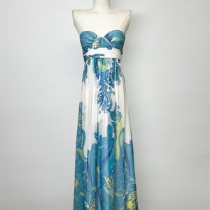 Könnte beinhalten: Trägerloses Maxikleid auf einer Schaufensterpuppe. Das Kleid hat ein blau-weißes Paisley-Muster. Das Oberteil ist dunkelblau mit einer Schleife. Der Rock ist weiß mit einem fließenden blau-gelben Design.