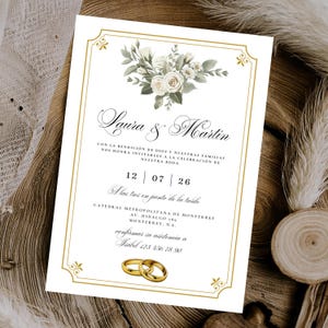 May include: Wedding invitation with floral design. The invitation features the names "Laura & Martin" in elegant script, along with event details and a gold ring graphic. The date is July 26th. The invitation is on a white background.