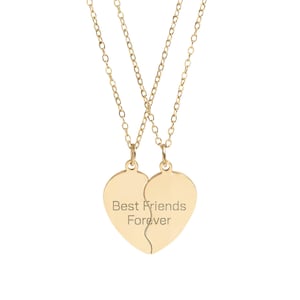 May include: A gold-colored necklace featuring two heart-shaped pendants that fit together. The pendants are inscribed with the words "Best Friends Forever". The necklace has a delicate chain.