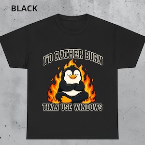 May include: A black short-sleeve t-shirt featuring a graphic of a penguin sitting in a meditative pose surrounded by orange and yellow flames. The text above the penguin reads I'D RATHER BURN and the text below reads THAN USE WINDOWS.