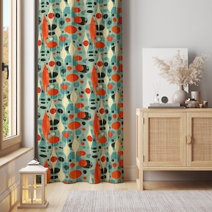 May include: A patterned curtain with a retro design. The curtain has a teal background with a repeating pattern of orange, white, and black oval and teardrop shapes. The curtain is hanging in front of a window.