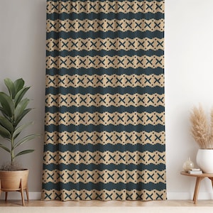 Puede incluir: Una cortina estampada con un diseño repetitivo de cruces y pinceladas azul oscuro sobre un fondo beige. La cortina cuelga frente a una pared blanca, con una planta en maceta y una pequeña mesa con un jarrón de flores secas visibles.