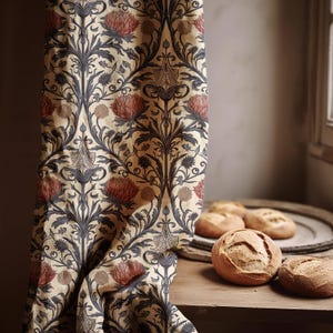 Puede incluir: Una cortina estampada con un fondo beige y un diseño repetido de flores rojas y hojas azul oscuro. Varias hogazas de pan redondas están sobre una mesa de madera.