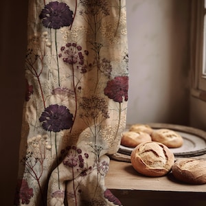 Peut inclure: Un rideau en tissu beige orné d'un imprimé botanique de fleurs violet foncé et rouge profond avec de fines tiges brunes et de petites grappes blanches. Le textile présente un motif floral répétitif avec de longues tiges fines.