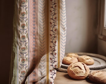 May include: A patterned fabric curtain with floral and geometric designs in shades of green, pink, and blue. The curtain is draped over a wooden surface with several loaves of bread.