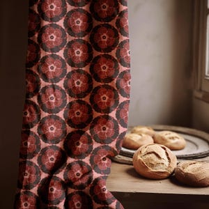 May include: A curtain featuring a repeating floral pattern in red and brown hues. The fabric hangs, revealing a wooden surface with several round loaves of bread. The colour scheme is warm and inviting, with the curtain's design dominating the image.