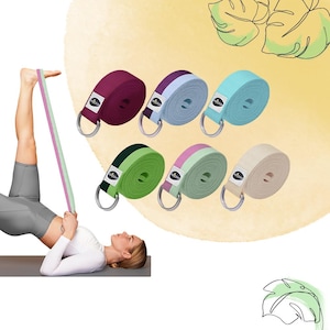 Könnte beinhalten: Yoga-Gurte in verschiedenen Farben, darunter Burgunderrot, Hellblau, Türkis, Grün und Beige. Jeder Gurt hat einen Metall-D-Ring und ein Etikett. Eine Person verwendet einen gestreiften Yoga-Gurt. Für Dehn- und Flexibilitätsübungen.
