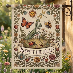 Puede incluir: Una bandera de jardín beige con una ilustración detallada de insectos y flores. Se representa una mariposa, una libélula, una abeja, una mariquita y una mantis religiosa. Las palabras "Respect the Locals" están escritas en una pancarta.
