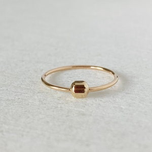 May include: A simple gold ring with a single, faceted, hexagonal bead.