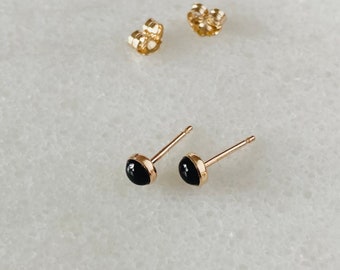 May include: A pair of gold stud earrings with black round stones.