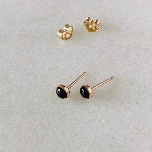 May include: A pair of gold stud earrings with black round stones.