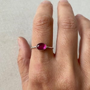 Könnte beinhalten: Ein silberner Ring mit einem rosafarbenen ovalen Edelstein.