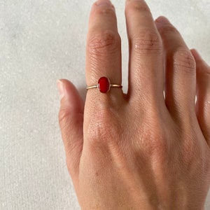 May include: A gold ring with a red oval gemstone.