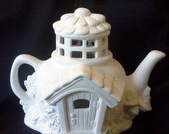 May include: White ceramic teapot shaped like a house with a flower-shaped roof and a small door. The teapot has a lattice window and a small porch.