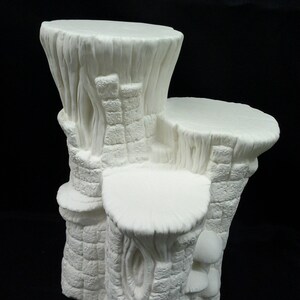 May include: White ceramic three-tiered stand shaped like a tree trunk with a rough texture. The stand has three circular platforms for displaying items.
