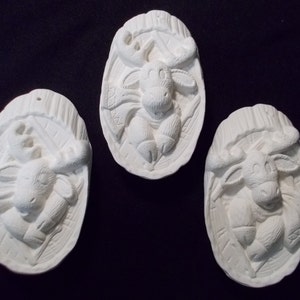 May include: Three white ceramic ornaments shaped like moose, each with a different pose. The ornaments are detailed with raised lines and have a rustic, woodland theme.