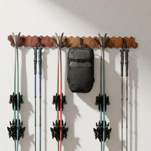 Puede incluir: Un estante de esquí de madera con varios pares de esquís, bastones de esquí y una mochila negra. Los esquís son de varios colores, incluyendo turquesa, rojo y blanco. El estante está montado en una pared blanca con un patrón geométrico.