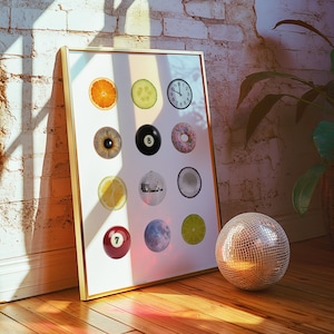 May include: A framed art print displaying various circular objects, such as a slice of orange, a cucumber, a clock, a pool ball, a donut, and a disco ball. A disco ball rests on the wooden floor in front of the print.