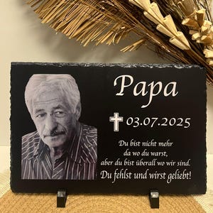 Könnte beinhalten: Schwarze Gedenktafel aus Schiefer mit dem Wort "Papa" und einem Foto eines Mannes. Das Datum "03.07.2025" steht unter einem Kreuz. Der Text lautet: "Du bist nicht mehr da wo du warst, aber du bist überall wo wir sind. Du fehlst und wirst geliebt!"
