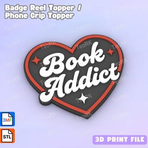 May include: A heart-shaped badge reel topper with the words "Book Addict" in white, outlined in black, and set against a gray background. The heart has a red border and star accents. The text "Badge Reel Topper / Phone Grip Topper" is at the top.