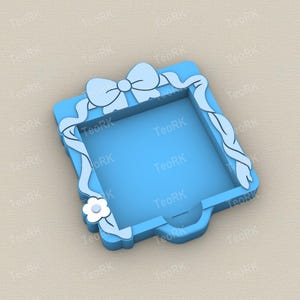 Puede incluir: Una bandeja decorativa cuadrada azul claro con un diseño de lazo y cinta. Una flor blanca está en el lateral. La bandeja tiene un asa pequeña. El texto "TeoRK" se repite alrededor de la bandeja.