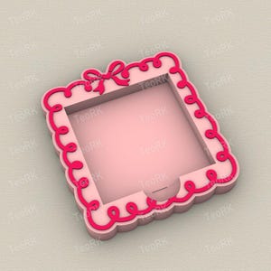 Op de afbeelding: Een roze vierkante doos met een decoratieve geschulpte rand en een strik aan de bovenkant. De doos heeft een donkerroze rand en een vierkante opening in het midden. De doos is ontworpen met een decoratieve, vrouwelijke esthetiek.