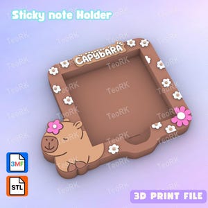 May include: A brown sticky note holder with a capybara design. The holder features the word "CAPYBARA" and is decorated with white and pink flowers. The text "Sticky note Holder" and "3D PRINT FILE" are also visible.