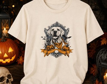 Può includere: Una t-shirt a maniche corte color crema con una stampa grafica di un cane che indossa una bandana, incorniciata da un bordo decorato con due zucche, un piccolo teschio e la sagoma di un pipistrello, centrata sul petto del capo.