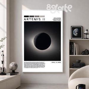 May include: A framed black and white poster titled "Artemis II" featuring a celestial body, possibly a planet or moon, with a bright halo. The poster includes text with names and the date "April 6, 2026".