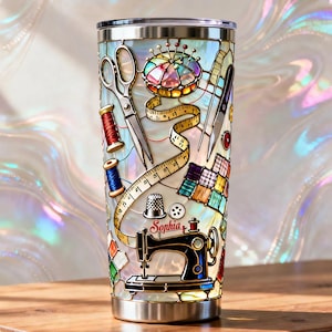 Könnte beinhalten: Edelstahlbecher mit einem Buntglas-Design von Nähwerkzeugen. Das Design umfasst Schere, Garnrollen, ein Maßband, eine Nähmaschine und den Namen "Sophia". Der Becher ist etwa 20 cm hoch.