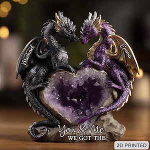 May include: A decorative figurine featuring two dragons facing each other, with a heart-shaped amethyst geode between them. One dragon is black, the other purple. The base reads "You & Me WE GOT THIS" with the names "Michael" and "Emma" on the wings.