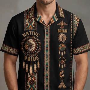 Può includere: Una camicia nera a maniche corte con bottoni e un tema nativo americano. Il design include il testo "NATIVE PRIDE" e "BRIAN", insieme a grafiche di un capo con copricapo, un uccello, acchiappasogni, un suonatore di flauto e un tepee.