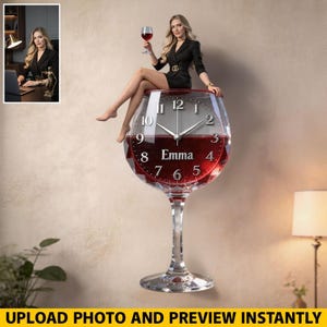 May include: A large, clear wine glass-shaped wall clock with a red liquid design. The clock face features silver hands, black numerals, and the name "Emma." A woman is sitting on the clock. The text "UPLOAD PHOTO AND PREVIEW INSTANTLY" is at the bottom.