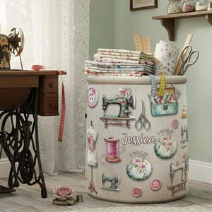May include: A cylindrical storage bin with a light beige textured surface, decorated with sewing-themed illustrations. The bin features images of sewing machines, scissors, and buttons. The name "Jessica" is printed on the bin.