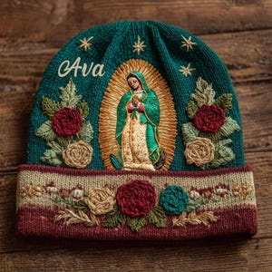 May include: Teal knit beanie with embroidered image of the Virgin Mary, surrounded by a gold halo. The word "Ava" is embroidered on the front. The brim features embroidered flowers in red, tan, and teal.